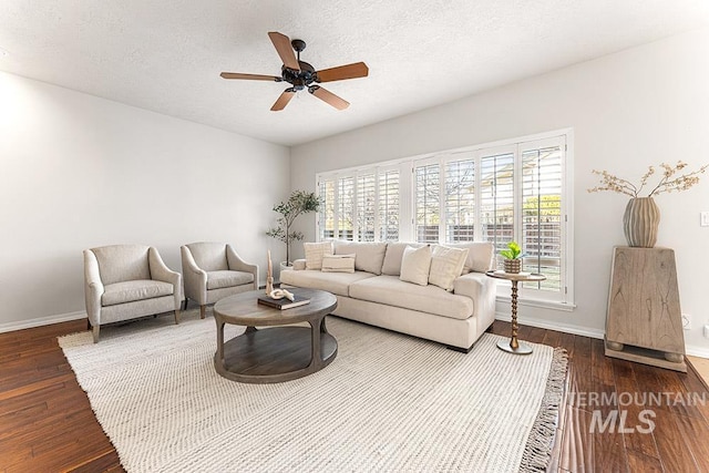 living room with dark wood finished floors, a textured ceiling, baseboards, and ceiling fan