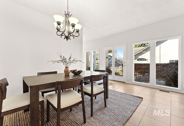 dining room with light tile patterned floors, visible vents, and a chandelier