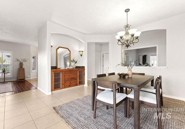 dining area featuring light tile patterned floors, a notable chandelier, and baseboards