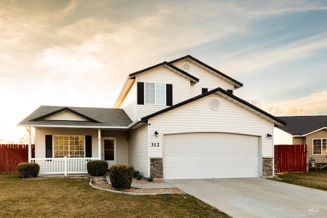 traditional-style home with concrete driveway, fence, covered porch, and a front lawn