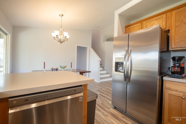 kitchen featuring light wood-style flooring, stainless steel appliances, light countertops, vaulted ceiling, and decorative light fixtures