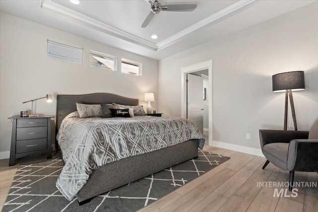 bedroom featuring hardwood / wood-style flooring, a raised ceiling, and ceiling fan