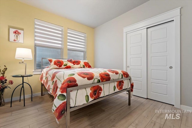 bedroom with light hardwood / wood-style floors and a closet