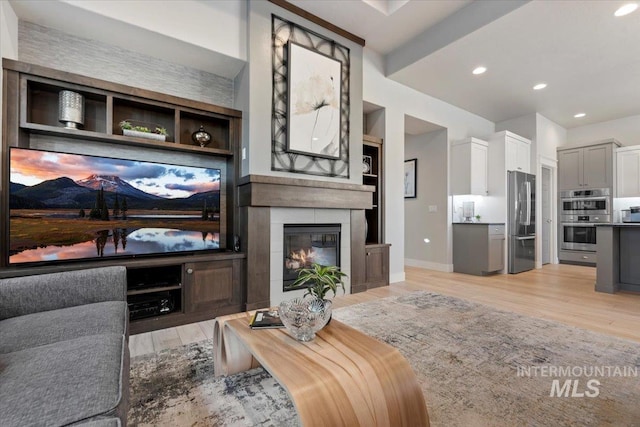 living room featuring a tiled fireplace and light hardwood / wood-style floors