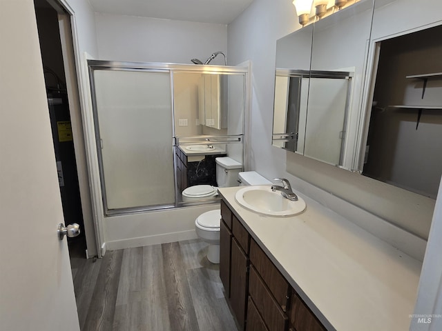 full bathroom with toilet, vanity, combined bath / shower with glass door, and wood-type flooring
