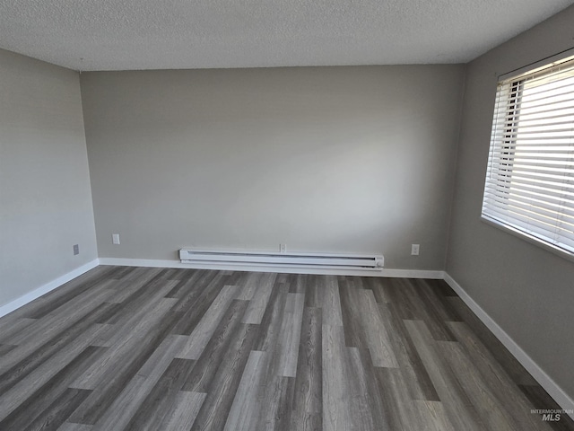 empty room featuring baseboard heating, dark hardwood / wood-style flooring, and a textured ceiling