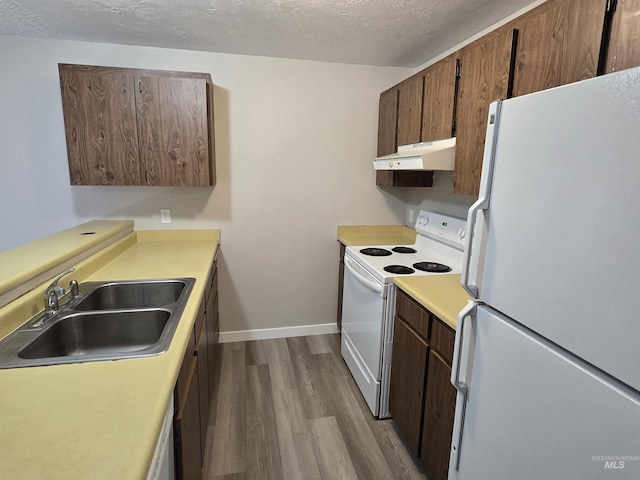 kitchen with white appliances, hardwood / wood-style flooring, sink, and a textured ceiling