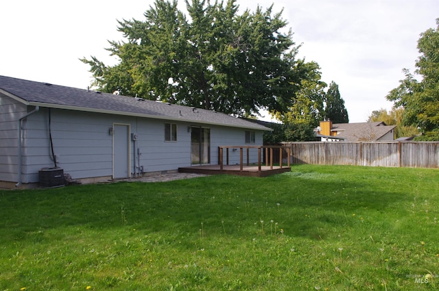 rear view of property with central AC unit, a wooden deck, and a lawn