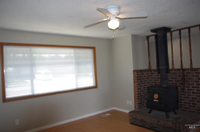 unfurnished living room featuring hardwood / wood-style flooring, a wood stove, and ceiling fan