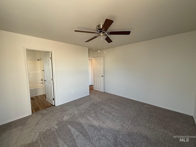 unfurnished bedroom featuring ensuite bathroom, ceiling fan, and dark carpet