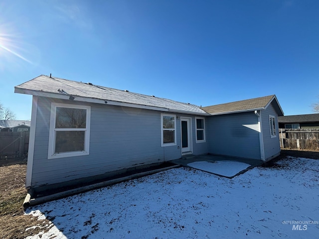 snow covered back of property with a patio area