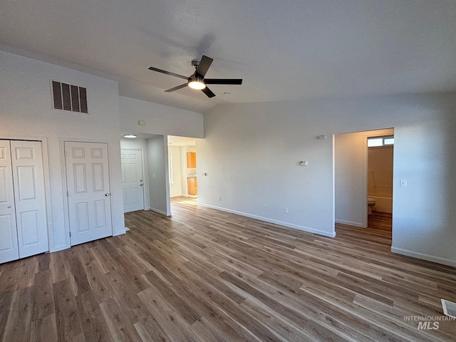 unfurnished bedroom with ceiling fan, multiple closets, hardwood / wood-style flooring, and lofted ceiling