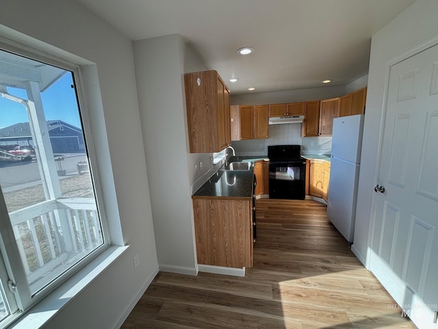 kitchen featuring tasteful backsplash, hardwood / wood-style floors, sink, black range with electric cooktop, and white refrigerator