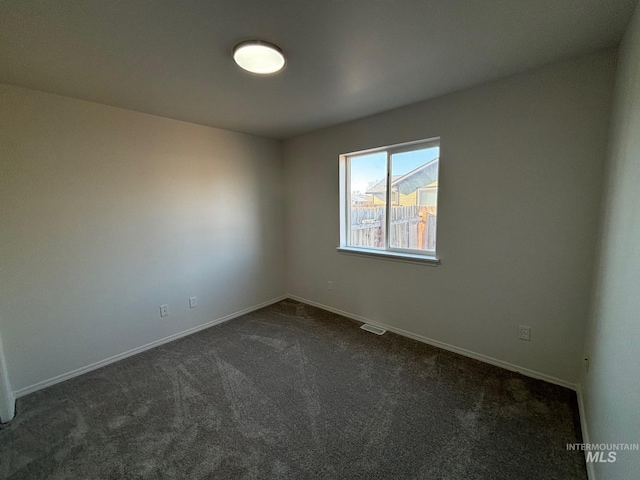 unfurnished room featuring dark carpet