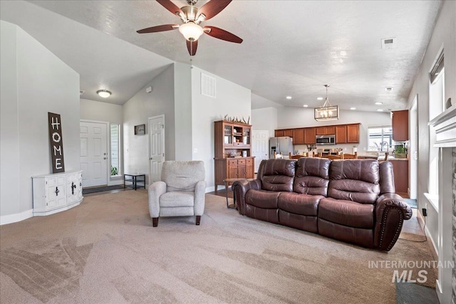 living area featuring vaulted ceiling, light carpet, ceiling fan, baseboards, and a chandelier