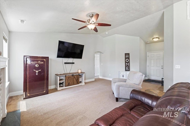 carpeted living room with ceiling fan, vaulted ceiling, baseboards, and a fireplace