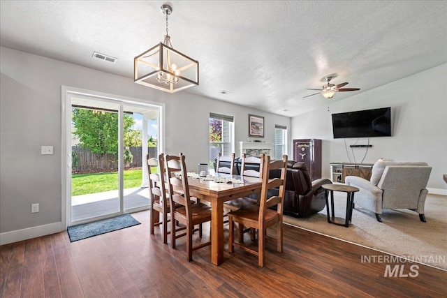 dining room with plenty of natural light, baseboards, dark wood-style flooring, a ceiling fan, and a textured ceiling