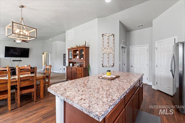 kitchen featuring freestanding refrigerator, open floor plan, a chandelier, dark wood-type flooring, and arched walkways