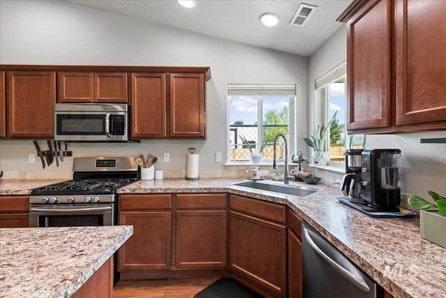 kitchen with stainless steel appliances, a sink, lofted ceiling, light countertops, and light wood-type flooring