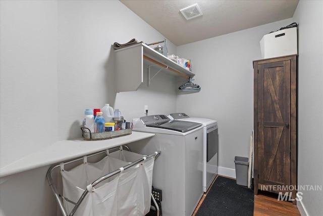 clothes washing area with separate washer and dryer, wood finished floors, and baseboards