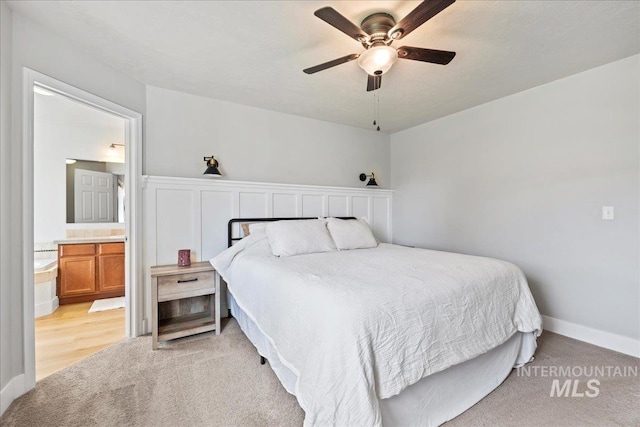 bedroom with light colored carpet, connected bathroom, ceiling fan, and baseboards