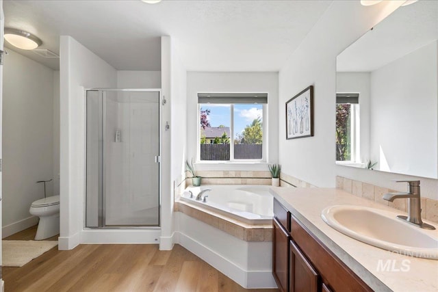 full bath featuring a shower stall, toilet, wood finished floors, vanity, and a bath