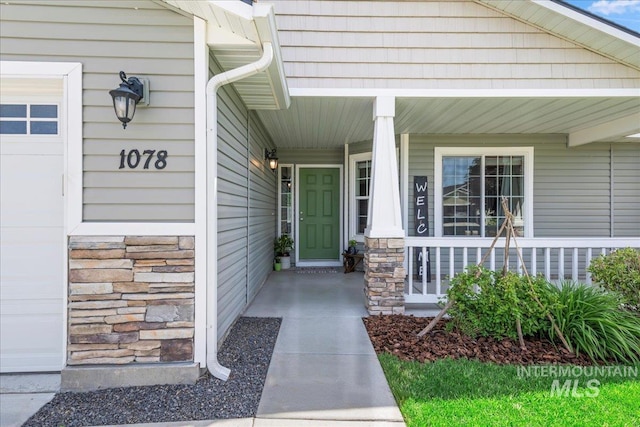 entrance to property with covered porch and stone siding
