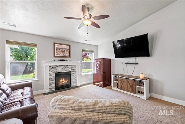 living room with ceiling fan, carpet flooring, lofted ceiling, baseboards, and a textured ceiling