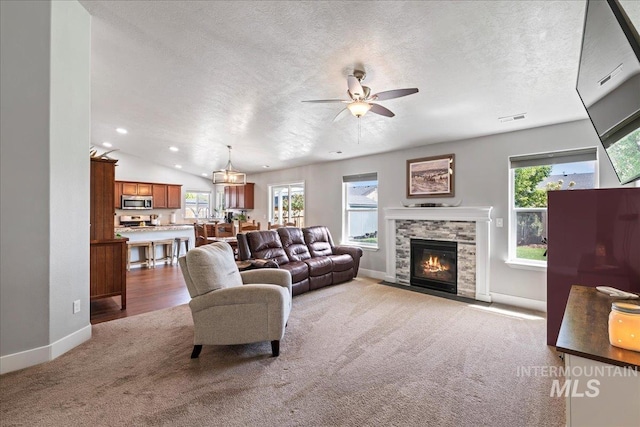 living area with carpet flooring, baseboards, healthy amount of natural light, a ceiling fan, and a textured ceiling