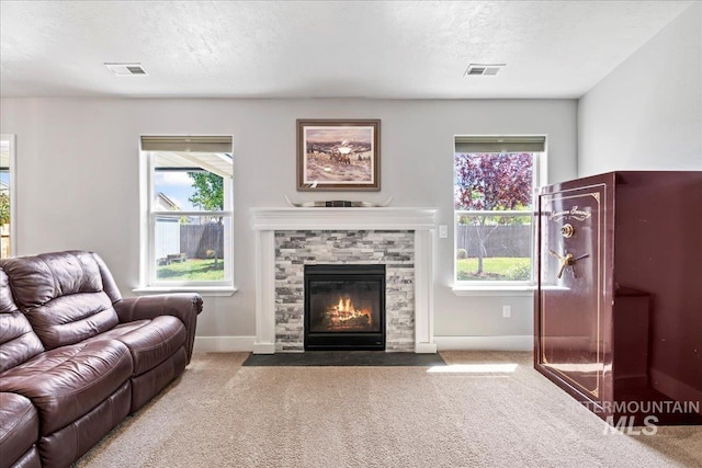 carpeted living room featuring baseboards, a stone fireplace, and a textured ceiling