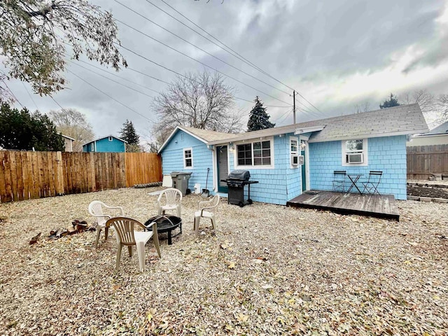 back of property featuring a deck, fence, and a fire pit