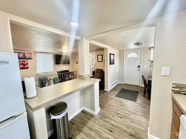 kitchen with a textured ceiling, white fridge, a baseboard radiator, and hardwood / wood-style flooring