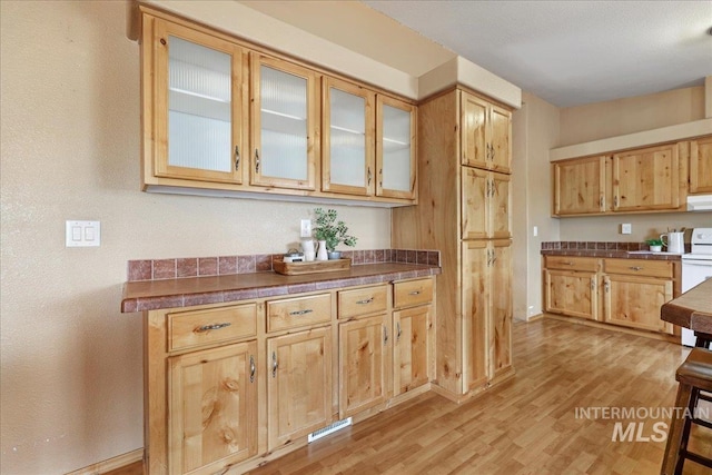 4240 N 1400 E, Buhl, ID 83316 - kitchen featuring light wood-style flooring, dark countertops, glass insert cabinets, and white electric range oven