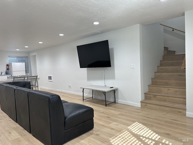 living room with recessed lighting, baseboards, light wood-style flooring, and stairs