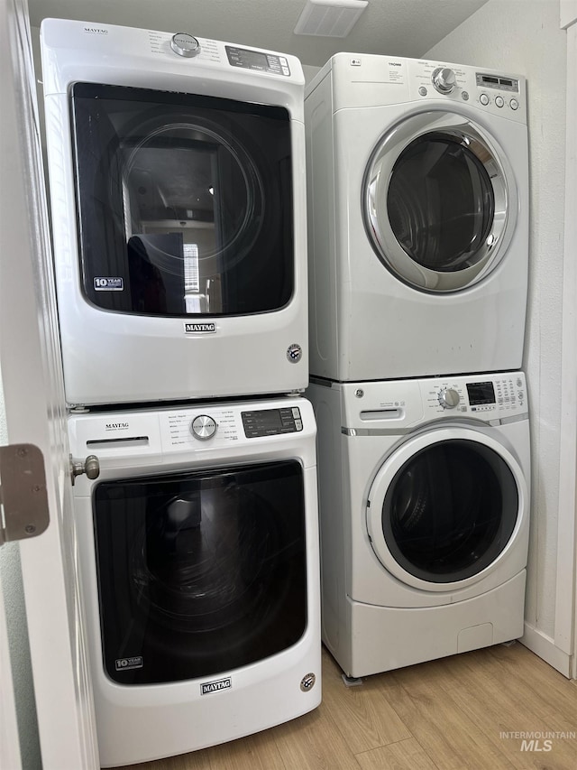 washroom featuring visible vents, light wood-style floors, laundry area, and stacked washer / dryer