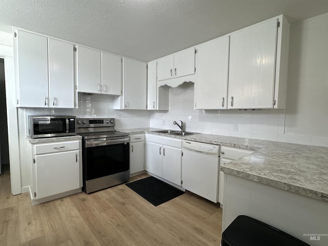 kitchen featuring a sink, stainless steel appliances, decorative backsplash, and light wood finished floors