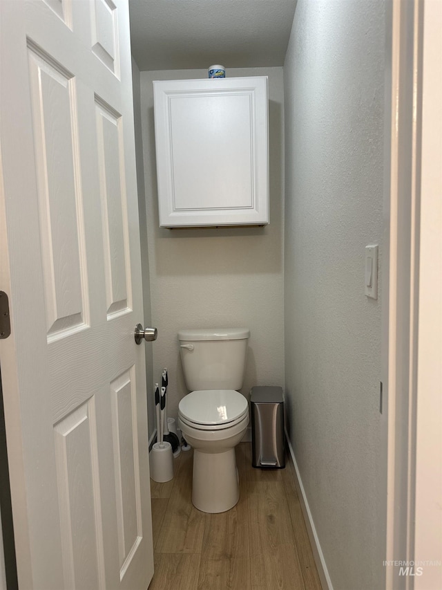 bathroom featuring baseboards, toilet, and wood finished floors