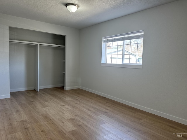 unfurnished bedroom featuring baseboards, a closet, and light wood finished floors