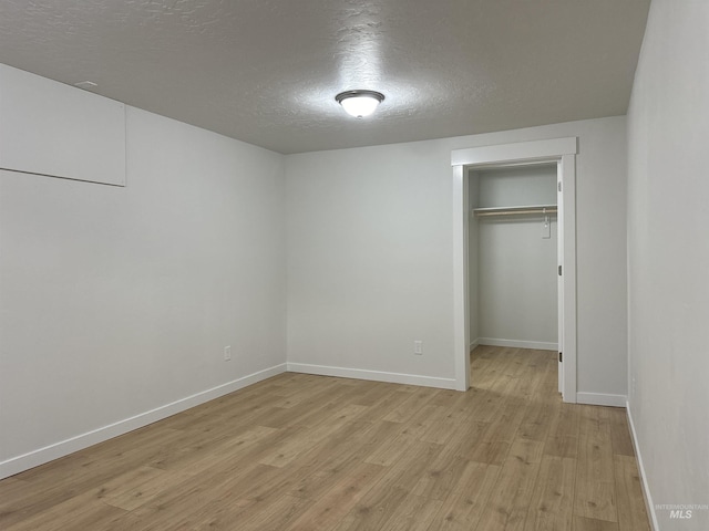 unfurnished bedroom featuring a textured ceiling, light wood-style floors, a closet, and baseboards