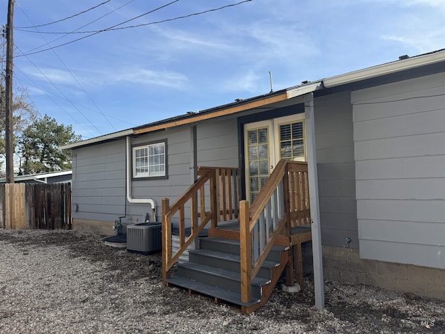 rear view of property with cooling unit and fence