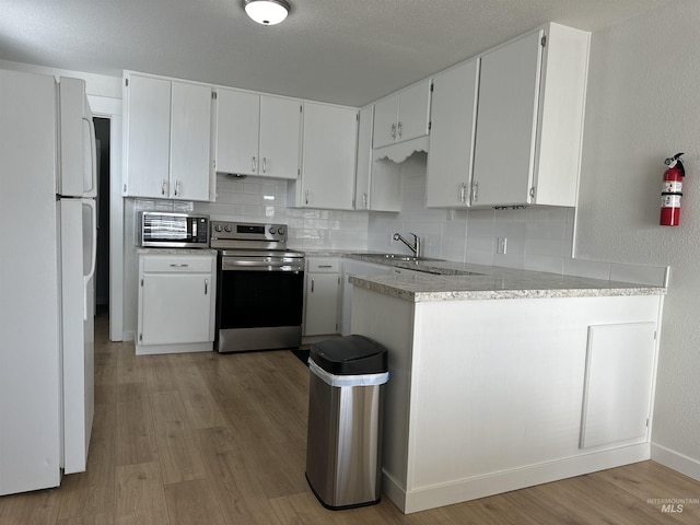 kitchen with backsplash, light wood finished floors, stainless steel electric range, and freestanding refrigerator