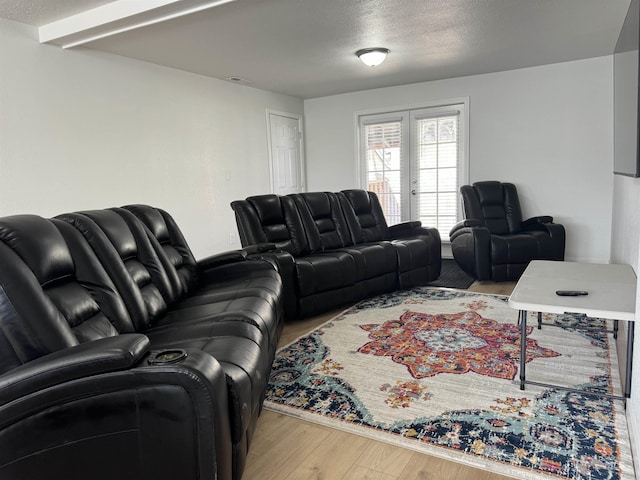 living room featuring french doors, a textured ceiling, visible vents, and wood finished floors