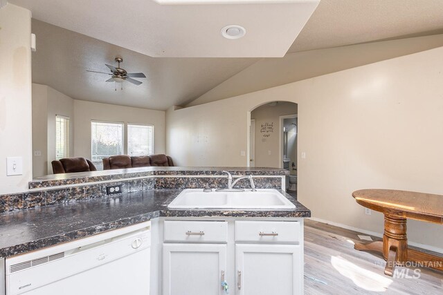 kitchen featuring dishwasher, a sink, arched walkways, light wood-type flooring, and white cabinetry