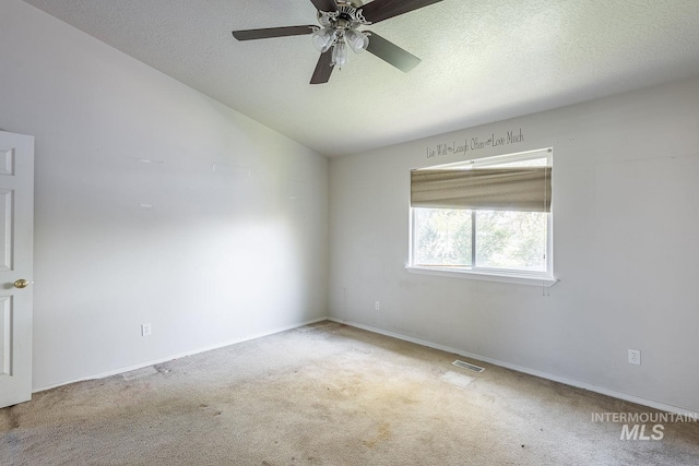 spare room featuring a textured ceiling, carpet flooring, visible vents, and a ceiling fan