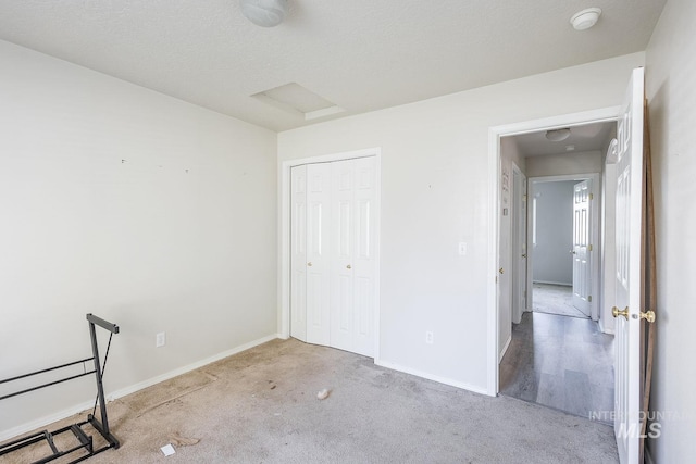 unfurnished bedroom featuring attic access, baseboards, carpet flooring, and a closet