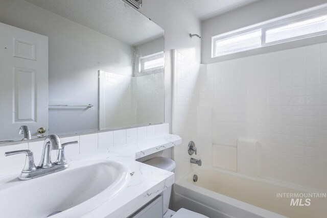 full bath featuring toilet, shower / bathtub combination, vanity, and a healthy amount of sunlight
