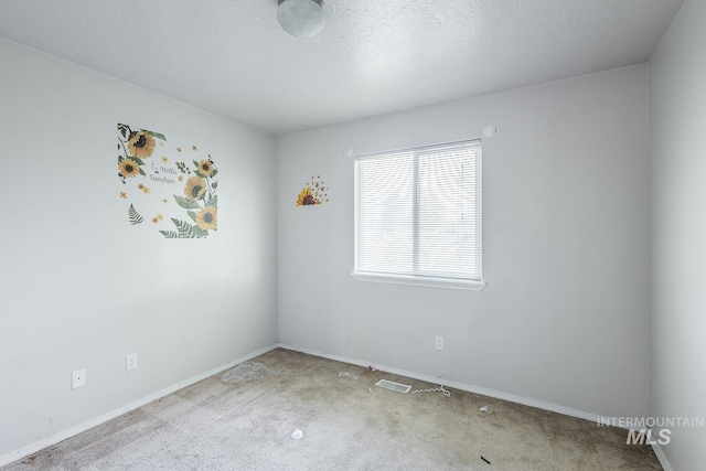 spare room featuring baseboards, carpet floors, and a textured ceiling