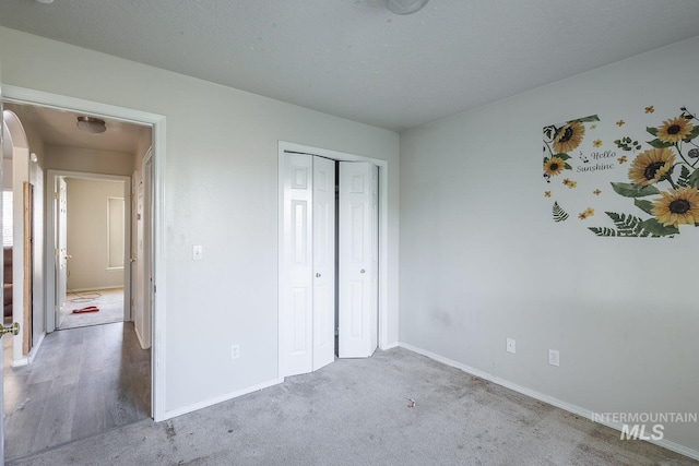 unfurnished bedroom with baseboards, a closet, and carpet