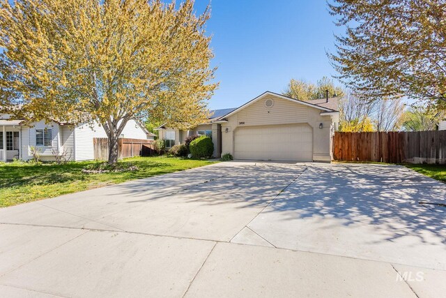 view of front of house featuring an attached garage, a front yard, fence, and driveway