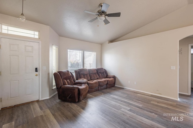 living room featuring wood finished floors, ceiling fan, arched walkways, baseboards, and lofted ceiling